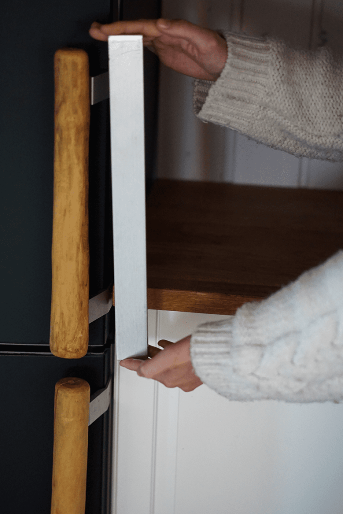 Old metal handle next to the new wooden handle of the fridge